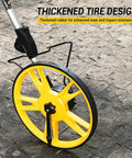 Digital Measuring Wheel With 12.5 Inch Wheel, Pro Grade Precision, Switchable Feet And Meters On Digital Display, Folding Roller With Storage Bag For Quick Distance Readings At Worksites And DIY Projects. yellow digital measuring wheel with thickened rubber tire on stone pavement