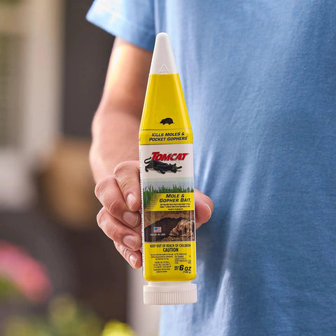 Person holding 6 oz Pelleted Mole And Gopher Bait For Fast Acting Pest Control In Lawns And Gardens, Easy To Apply in yellow bottle.