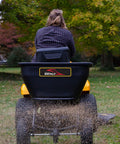Tow Behind Broadcast Spreader With Universal Hitch 175 Lb Capacity Durable Poly Hopper spreading grass seed on lawn