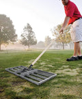Person using 30-Inch Lawn Leveling Rake With 72-Inch Handle, Stainless Steel Tray on golf course for lawn leveling.