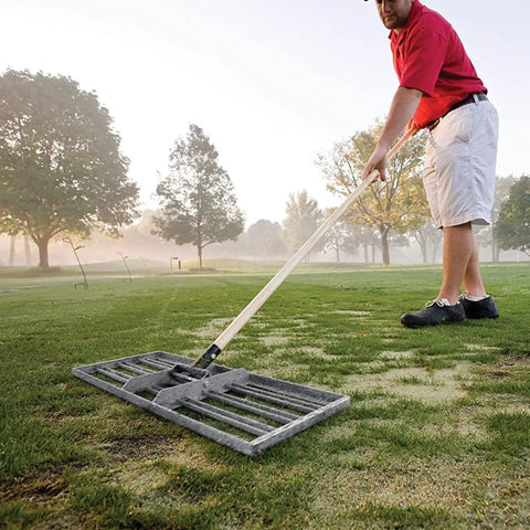 Person using 30-Inch Lawn Leveling Rake With 72-Inch Handle, Stainless Steel Tray on golf course for lawn leveling.