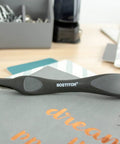 Ergonomic black office staple remover with magnetic pick up, placed on a desk, highlighting its sleek push-style design.