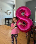 Child holding a Hot Pink Number 8 Balloon 40 Inch Giant Foil Balloon For 8th Birthday Party Decor Epic Photo Backdrop Prop.