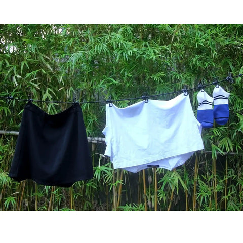 Portable Retractable Clothesline For Camping And RV Life With 12 Clothespins, black and white clothes hung outdoors in garden