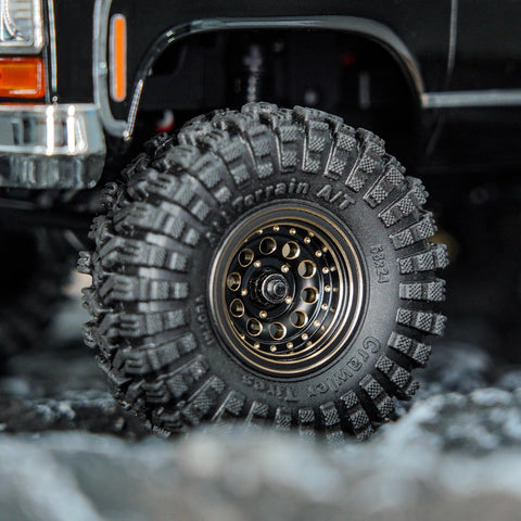 Close-up of Brass Beadlock Wheel Set With Black Coating And S5 1.0 Crawler Tires For Axial SCX24 AX24 TRX4M FCX24 Upgrades 1/24 1/18 RC Crawlers Negative Offset For Wider Stance Durable Bias Ply Build And Aggressive Side Lug installed on RC crawler with rugged tire tread.