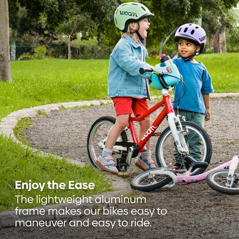 Two kids with helmets and bikes in a park, featuring Go 3 Automagic 16 Inch Kids Bicycle With Automatic Two Speed Shifter Hand Brakes.