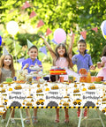 Children celebrating with Construction Themed 1st Birthday Party Decor Dump Truck Dinnerware Set on a table outdoors.