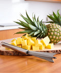 V Shape Pineapple Eye Remover Tool With Multipurpose Clip Stainless Steel Peeler on kitchen counter with sliced pineapples