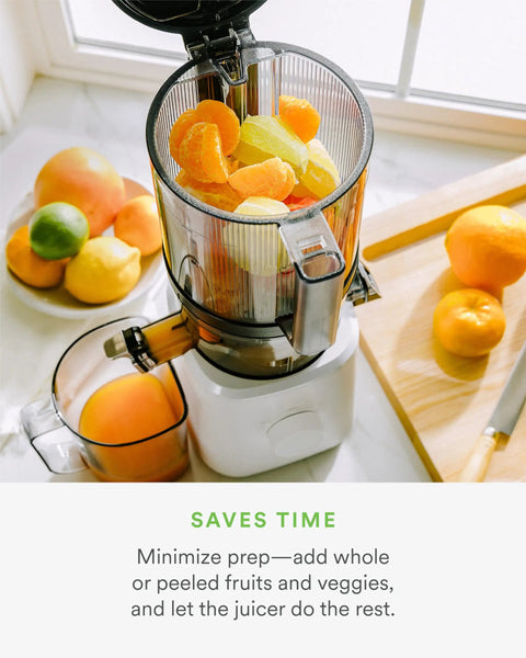 Nama J2 Cold Press Juicer Hands Free White Self Feeding Hopper filled with fruits, clear container visible, placed in kitchen setting.