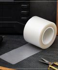 Urethane Die Protection Film For Press Brake Dies Pro Grade Die Guard Tape To Prevent Scratches On Stainless Steel And Aluminum During Metal Bending 4 Inch By 0.030 Inch By 100 Feet roll displayed on a worktable, showing its clear material and thickness.