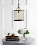 10-Inch Black And Brass Gold 1-Light Iron Pendant Lantern hanging over a table with flowers and books, modern drum design