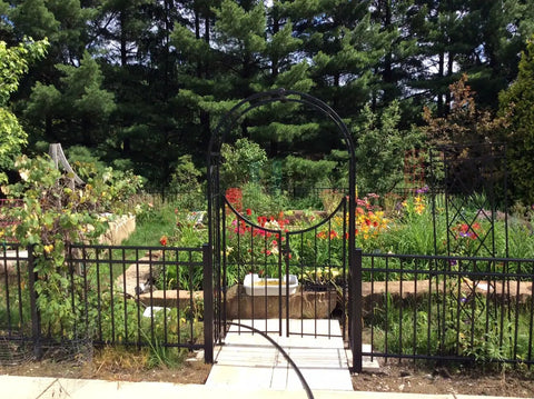 Arched Top Garden Arbor With Gate Brushed Bronze Powder Coated Outdoor Garden Archway in a serene garden setting