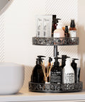 Two-tier metal Lazy Susan organizer turntable, black finish with floral filigree, 12-inch; holds bottles and pumps.