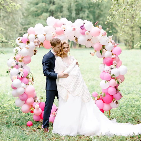 Bride and groom posing in front of pink and white balloon arch, part of White Balloons Party Kit 129 Pcs Mixed Sizes.
