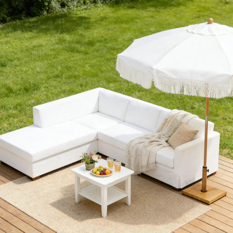 Outdoor patio with white sofa, coffee table, and umbrella on wooden deck.