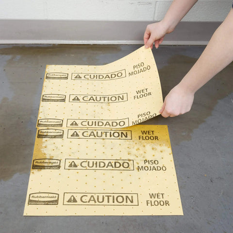 Yellow Spill Pad Refills For Water And Oil Absorbent Mats showing caution sign being placed on a wet floor.