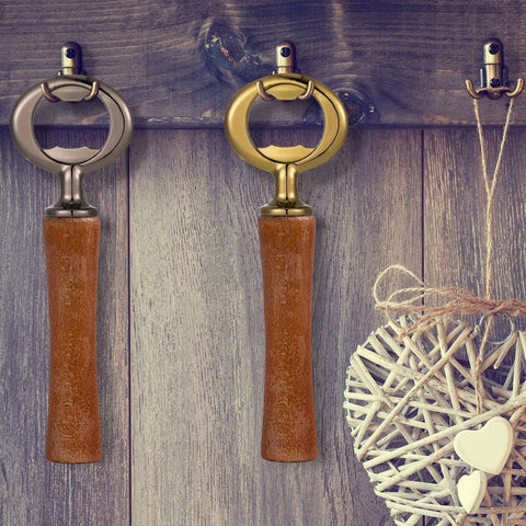 Two wooden-handle bottle openers with gunmetal and brass heads hanging on a rustic wood wall.