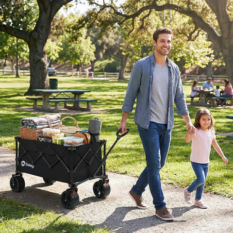 Man pulling Foldable Wagon With All Terrain Wheels Beefy 150L Capacity Heavy Duty Collapsible Cart, picnic items inside, park setting