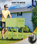 Person pushing 80 Quart Rolling Ice Chest Cooler Cart For Patio Parties And Party Ready Backyard Bar Setup With Folding Shelf And Bottle Opener Light Green Portable Beverage Cooler On Wheels in garden.