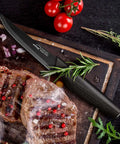 Eight Piece Steak Knife Set With Stainless Steel Serrated Blades, Rust Resistant Nonstick Coating; black handle knife next to steak and herbs