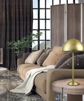 Haydel 21 Inch 2 Light Table Lamp in matte brass with dual pull chains in a modern living room setting, placed on a side table.