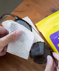 See Clear Lens Cleaning Wipes used on tortoiseshell sunglasses; white dotted wipe; yellow packaging in background