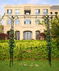 Steel Garden Arch For Climbing Plants 6 Ft 9 In High By 4 Ft 11 In Wide Weather Resistant Black Epoxy Finish Outdoor Yard Arbor Built To Show Off Vines And Flowers Easy Setup For Your Patio Garden Lawn Backyard in front of a building