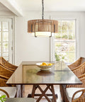 A Straight Up Game Changer 4Light Rattan Chandelier With Linen Drum Shades hanging over a wooden dining table with wicker chairs.