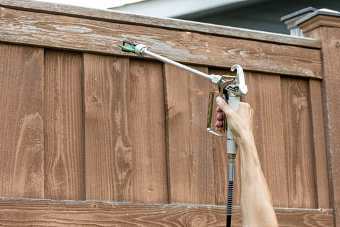 Hand using 12 Inch HEA Extension for High Efficiency Airless Sprayers to paint wooden fence, adds one foot of reach to Control Pro or Titan ControlMax
