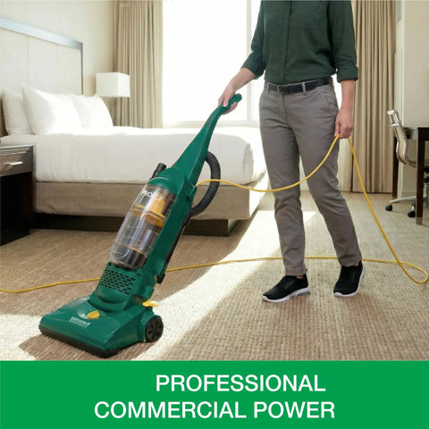 Heavy Duty Bagless Upright Vacuum Chomping Debris On Carpets Hardwood Floors And Furniture With Beastly Suction Plus Onboard Tools And Commercial Filtering For Daily Grind Cleaning in a hotel room.