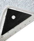 Black triangle gripper under rug showing Eight Pack Rug Tape Grippers For Rugs Reusable Washable Non Slip Double Sided Rug Pads