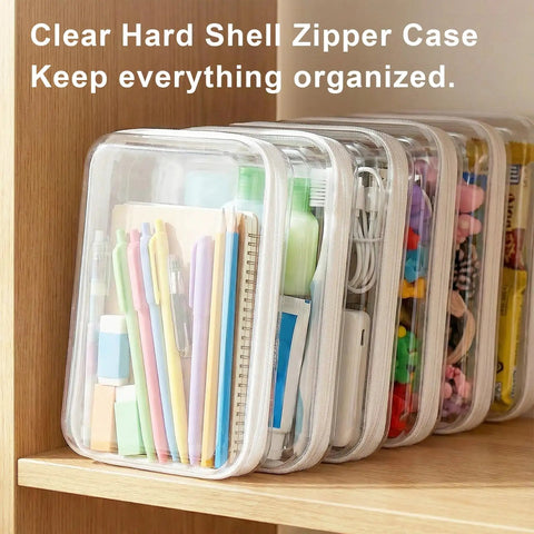 Must Have Clear Hard Shell Zipper Case Three Pack Large 9.84 Inches By 7.87 Inches By 2 Inches Waterproof Storage Pouches For Toys Travel Makeup And Small Items Transparent Organizer Bags filled with stationery items on a shelf.