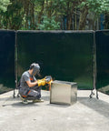 Welder using Six By Eight Foot 3-Panel Welding Screen With Frame, Flame-Resistant Vinyl Safety Curtain, 12 Wheels, Dark Green outdoors.