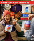 Person enjoying Fettuccine Alfredo With Chicken Freeze Dried Camping Meal For Outdoors Creamy Comfort Food by a packed car trunk.