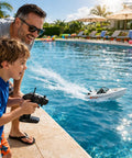 Father and son playing with Jet Propulsion RC Boat With Brushless Motor For Beginners A Mini Yacht Style Remote Control Boat For Kids Waterproof Electric Boat For Pool Lake And River Grey by the poolside