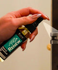 Hand applying Renew Natural Household Oil Unscented All Purpose Lubricant Spray For Doors Hinges And Locks Eco Conscious to a door hinge