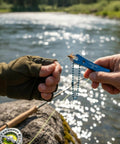 Person using Stainless Steel Fishing Line Nipper Cutter With Keychain For Fly Fishing Dope Compact Tool by the river.