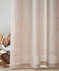 Child playing behind Candy Stripe Linen Curtains For Kids Room Two Panels 96 Inch Length Kid Friendly Grommet Window Treatments