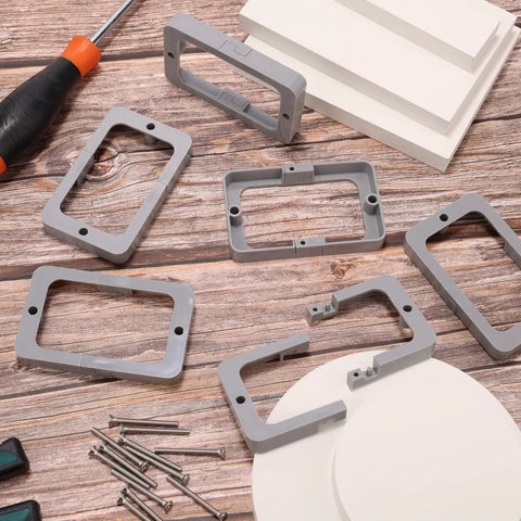 Six Pack Half Inch Single Gang Receptacle Box Extenders with screws, gray, shown on a wooden surface with installation tools