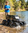 Child playing with Amphibious One Twelfth Scale 8WD Remote Control Monster Truck For Land And Water Waterproof All Terrain RC Toy by lake.