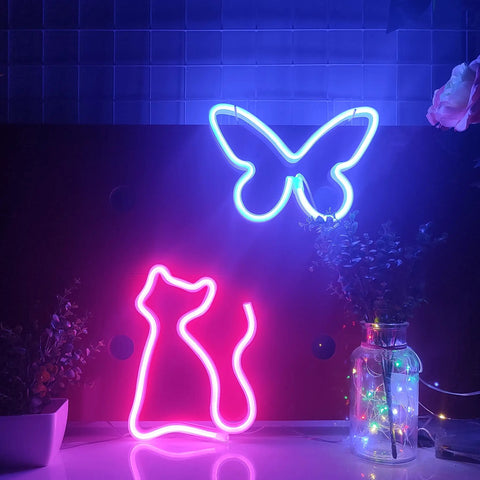 Pink Cat Neon Sign LED Light powered by USB or three AA batteries on desk, butterfly design above, vibrant purple and pink glow