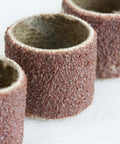 Close-up view of brown abrasive sanding drums for rotary tool; five cylindrical sleeves.