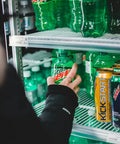 Hand reaching for a bottle of Mountain Dew in a Top Shelf Commercial 3 Door Reach In Refrigerator, Built Tough Stainless Steel Display Cooler Merchandiser For Every Kitchen Grind, Roomy 72 Cubic Foot Layout.