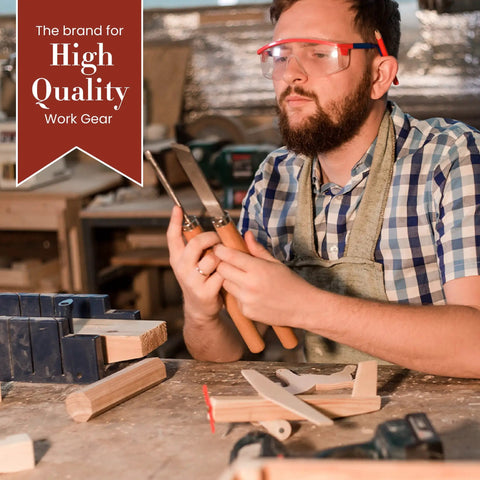 Carpenter holding tools in workshop, wearing protective eyewear and apron, surrounded by wood and instruments, promotional sign for work gear.