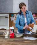 Woman using Plaster Of Paris Dry Mix White 8 Lb Tub for DIY interior wall repair and craft projects, quick set in 20 to 30 minutes.