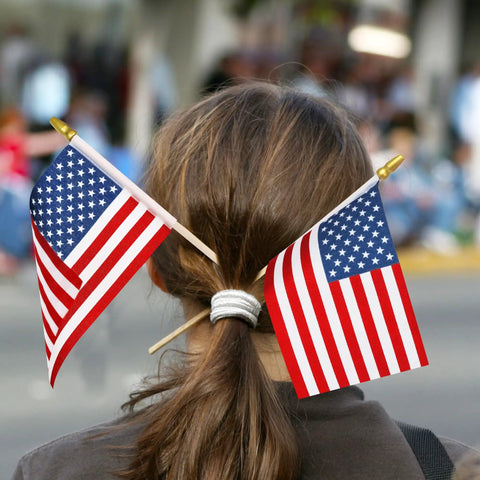 Girl with 50 Pack 4x6 Inch American Flags on sticks in hair during Fourth of July parade, showcasing tear-resistant handheld USA flags.