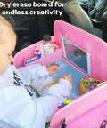 Child using Kids Travel Tray for Car Seat with Ipad Holder and Dry Erase Board Toddler Lap Desk for Road Trips Portable Car Tray with Snack Surface and Activity Tabs Pink in a car.