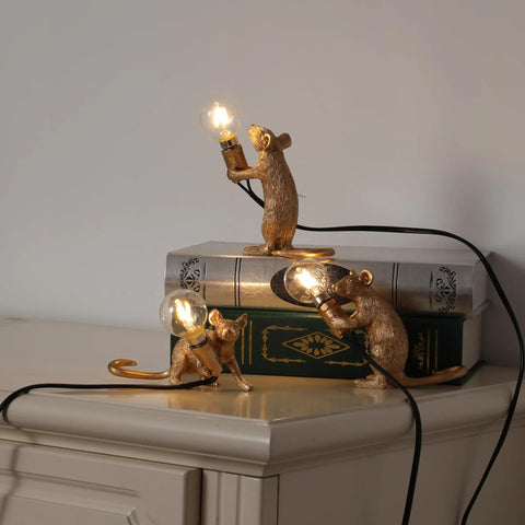 Three Style Resin Mouse Desk Lamp With LED Glow Featuring Running Sitting And Standing Cute Mouse Figures In Gold Finish For Bedroom Or Study Room Decor Plug In Table Light With Easy On Off Switch on a shelf.