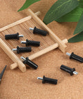 8 Piece Black Metal Cabinet Door Damper Pins Spring Loaded Telescopic Pivot Pins For Cabinet Doors And Shutters Furniture Repair And Maintenance Kit For Quick Home Repairs with pliers and plant leaves background