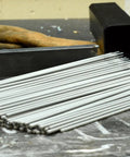 5 64th Inch E6013 Arc Welding Electrodes, 5 Pound Pack, All Purpose Welding Rods For Mild Steel, Easy To Start At Low Amps, Works In All Positions, 60,000 PSI Weld Strength, Best On Clean Light Gauge Metal, Great For Beginners To Pros. Stack of 5/64 inch E6013 rods on a workbench